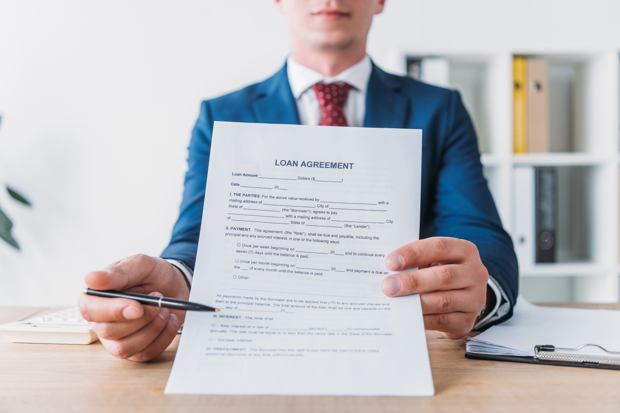 cropped view of manager pointing with pen at loan agreement